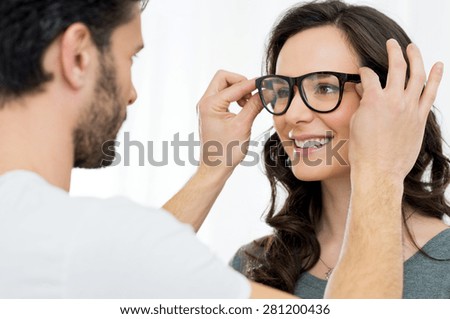 Optician putting a new pair of eyeglasses on a patient
