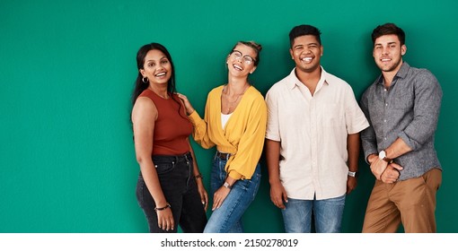 Optimism is a strategy for making a better future. Portrait of a group of young designers standing together against a green background.