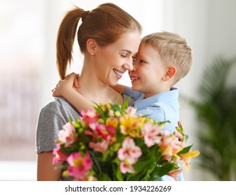 Optimistic Family: Mother With Bouquet Of  Alstroemeria Laughing And Touching Nose With Happy Son  During Holiday Celebration  Mothers Day At Home