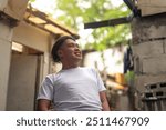 An optimistic man looking up while in front of a slum area. A young Filipino residing in an squatter area. Shantytown background.