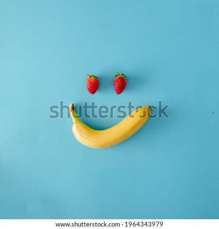 Optimistic spring arraignment. Strawberries and banana on a pastel blue background. Minimal creative flat lay.