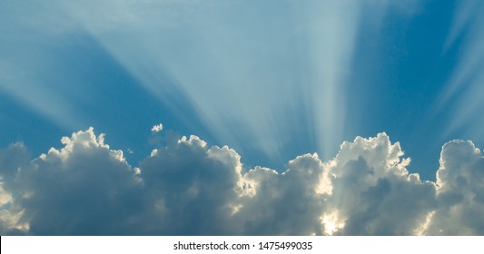 Optimistic sunset rays behind the clouds. Glow in the sky. Symbol of light. Beautiful scene of nature.
