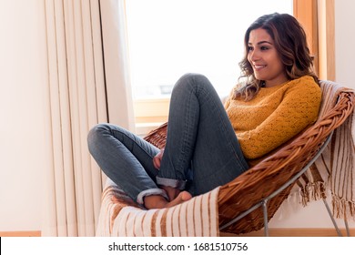 Optimistic woman sitting in a confortable rattan chair at home