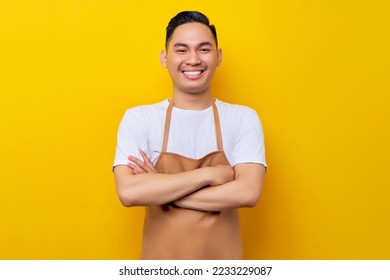 Optimistic young Asian man 20s barista employee wearing brown apron working in coffee shop, standing with crossed arms, looking on camera with toothy smile on yellow background. Small business startup - Powered by Shutterstock