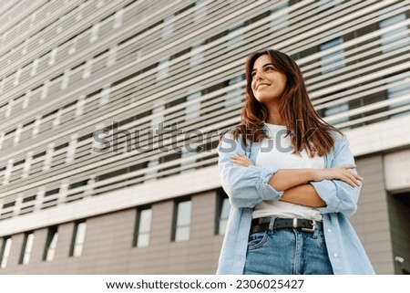 Optimistic young caucasian woman standing looking to the side with crossed arms - Female ambition