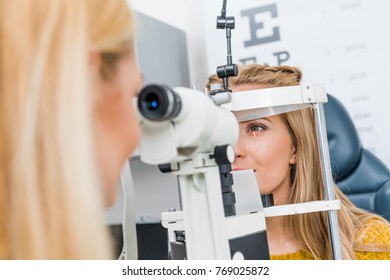 optometrist examining patient through slit lamp in clinic - Shutterstock ID 769025872