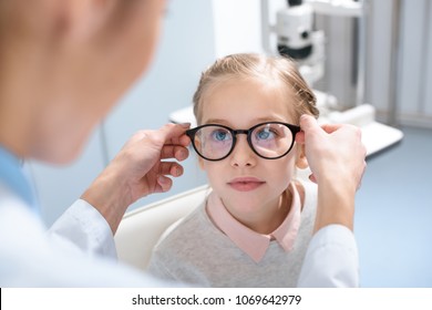 optometrist and little kid in glasses in optics  - Powered by Shutterstock