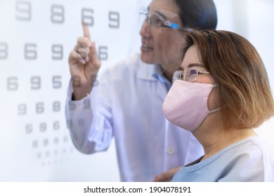 Optometrist Man Checking Senior Asian Woman Patient Vision, Asian Senior Woman Wearing Protection Mask 