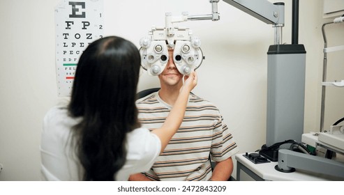 Optometrist, man and phoropter for eye exam, vision and wellness in consultation room at hospital. People, doctor and help patient with machine, lens and assessment for healthy eyesight in clinic - Powered by Shutterstock