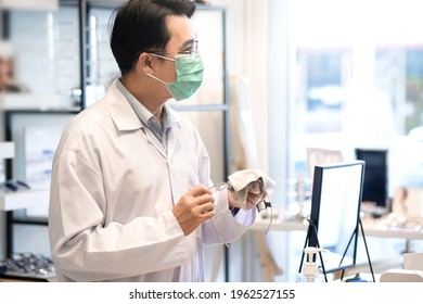 Optometrist Or Optician Wearing Medical Mask Checking Glasses In Optician Shop, Glasses For Sale 