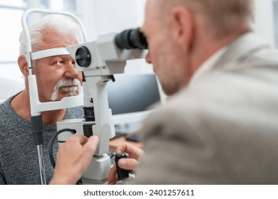 Optometrist using a slit lamp to examine a senior man's eye at the clinic. Close-up photo. Healthcare and medicine concept - Powered by Shutterstock