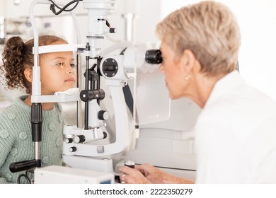 Optometry, vision and optometrist doing eye test on girl for optical care, wellness and health. Senior optician doing optic examination on child with autorefractor equipment in eyewear clinic or shop - Powered by Shutterstock