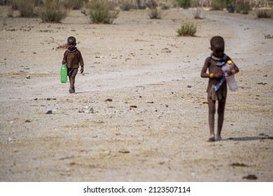 OPUWO, NAMIBIA - Nov 20, 2012: Opuwo, Namibia, November 2012: African Kids Carrying Plastic Water Bottles On A Dirt Road