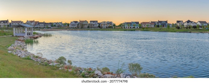 Oquirrh Lake with covered dock and surrounded by grass at Daybreak, Utah