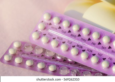 Oral contraceptive with frangipani flowers on pink frieze cloth background with warm light tone.