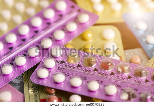 Oral contraceptive pill on pharmacy counter\
with colorful pills strips\
background.