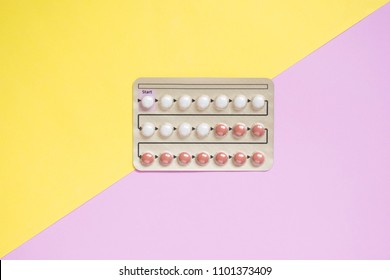 Oral contraceptive pills blister on yellow pink background. Hormones used to prevent pregnancy and treat other medical conditions, such as PCOS, endometriosis, amenorrhea or acne. Gynecology concept.