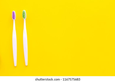 Oral Hygeine. Toothbrushes On Yellow Background Top View Copy Space