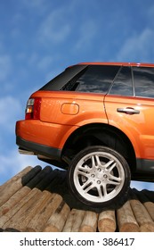 orange 4 x 4 on wooden logs - rear view - Shutterstock ID 386417