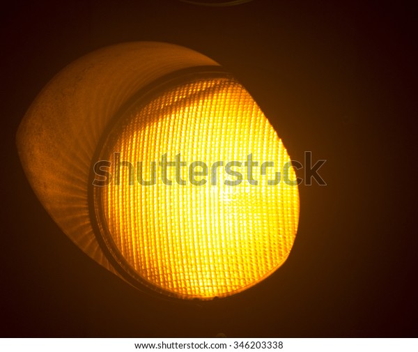 Orange amber traffic light photo at night on\
black background.