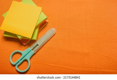 orange background with paper and scissors