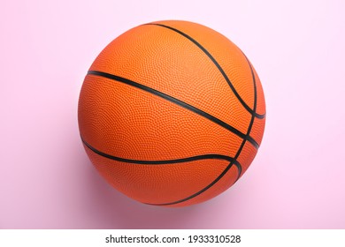 Orange ball on pink background, top view. Basketball equipment