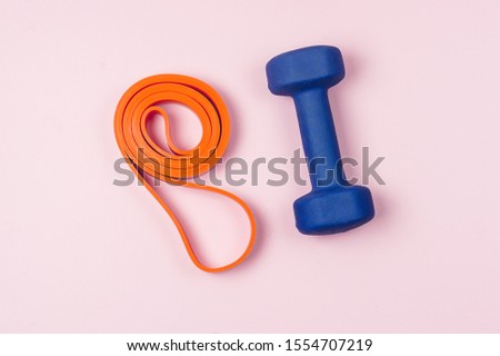 Orange Band for Fitness or Exercise and Blue Dummbell on Pink Background Top View Flat Lay Horizontal Weight Loss Concept