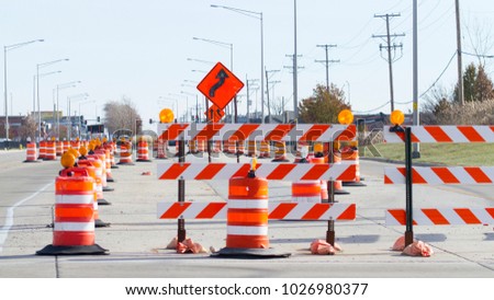 Orange barrels, barricades, and signs blocking a road