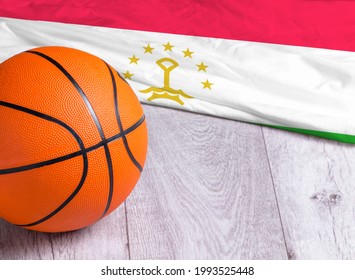 Orange Basketball Ball With Flag Tajikistan On Wooden Parquet. Close-up Image Of Basketball Ball Over Floor In The Gym. Basketball Championship Concept