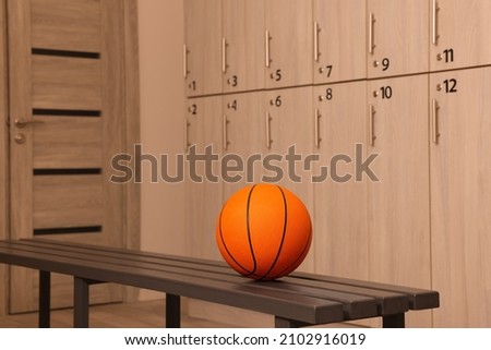 Orange basketball ball on wooden bench in locker room