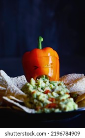 Orange Bell Pepper As Monster With Cut Out Face Carved Into A Halloween Pumpkin Jack O'Lantern Throwing Up Guacamole Served With Chips. Selective Focus On Mouth With Blurred Foreground And Background.