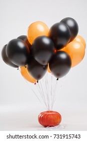 Orange And Black Balloons And A Pumpkin For A Halloween Party On A Light Background. Halloween Decorations.