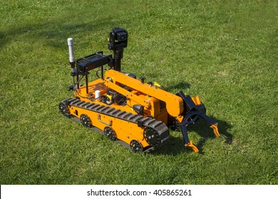 Orange bomb disposal robot on the grass with arm folded