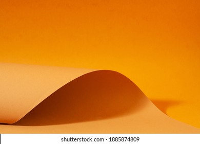Orange and brown paper is curved by a wavy line, beautiful soft light and shadow on paper, abstract background for designers.