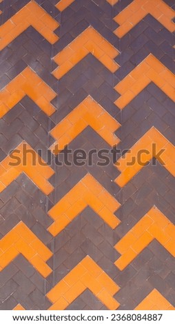 Orange and brown tiles in the form of a triangular border on an antique wall.