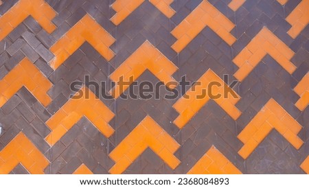 Orange and brown tiles in the form of a triangular border on an antique wall.