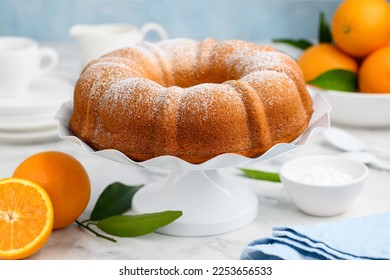 Orange bundt cake dusted with powdered sugar on a white stand. Fruity citrus dessert. Selective focus - Shutterstock ID 2253656533