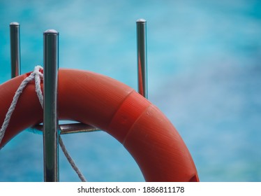 orange buoy hanging on stainlesssteel blu and blur background of water