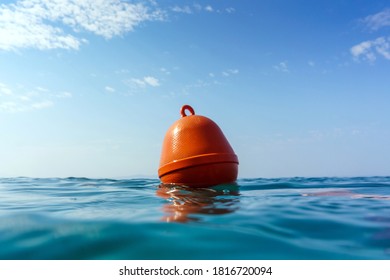 Orange buoy in the waves of the Adriatic Sea. Human life saving concept, SOS, water rescue. Selective focus, summer day. Makarska, Croatia, Europe.