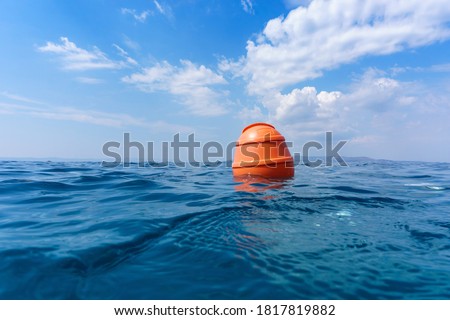 Orange buoy in the waves of the Adriatic Sea. Human life saving concept, S.O.S., water rescue. Selective focus, summer day. Makarska, Croatia, Europe.