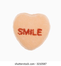 Orange Candy Heart That Reads Smile Against White Background.