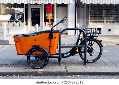 Orange cargo bike parked on a london sidewalk - Powered by Shutterstock