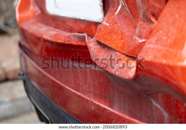 Orange car\'s back bumper is broken. Crashed car\
destroyed automobile part. Insurance of car crash is important.\
Destroyed red car