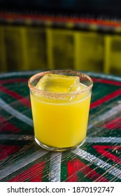 An Orange Cocktail In A Rocks Glass With A Big Ice Cube And Spicy Rim On The Glass