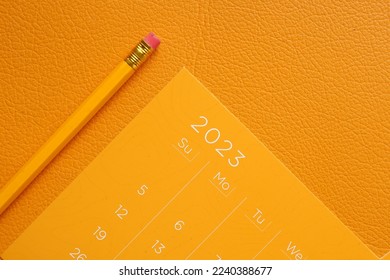orange color 2023 year calendar and a pencil on table  - Shutterstock ID 2240388677