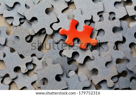 Orange color puzzle piece standing out from larger group of puzzle pieces. Business concept and ideas- branding, different, original. No people. Copy Space