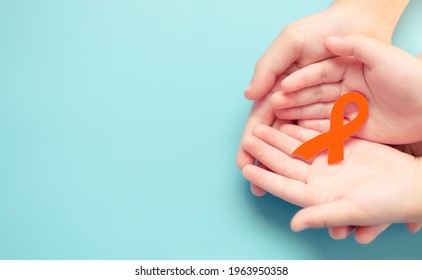 Orange Color Ribbon In Mother And Family Child Hand For Kidney Cancer Disease Awareness.leukemia Day.treatment Care, Support, Charity, Hope.medical.Multiple Sclerosis.COPD And ADHD.leukemia Child.