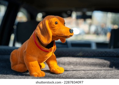 Orange colored nodding dog in the back of a car