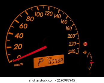 Orange colored vehicle dashboard with 80088 km odometer. Close up speed odometer of stop car.