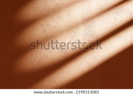Orange concrete facade with sunlight shadow background. Indoor shade from window light on texture pastel wall. 
